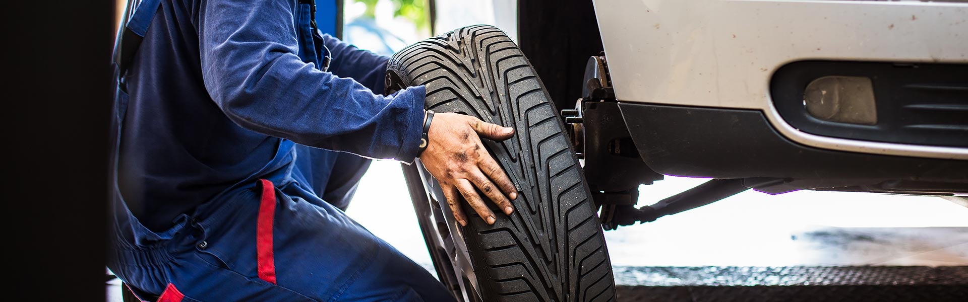 Mechanic installing a tire on a vehicle elevated on a lift